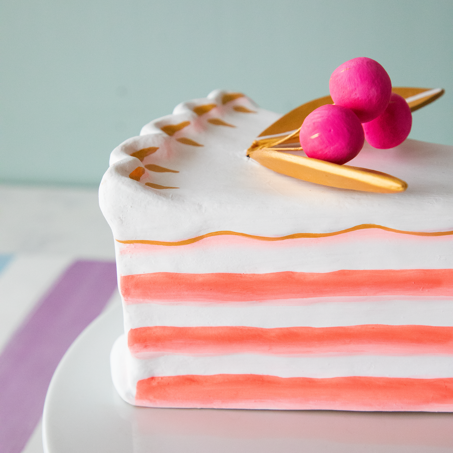 A stack of plates with Glitterville Large French Cake Slices with Gold Leaf on them for a party.