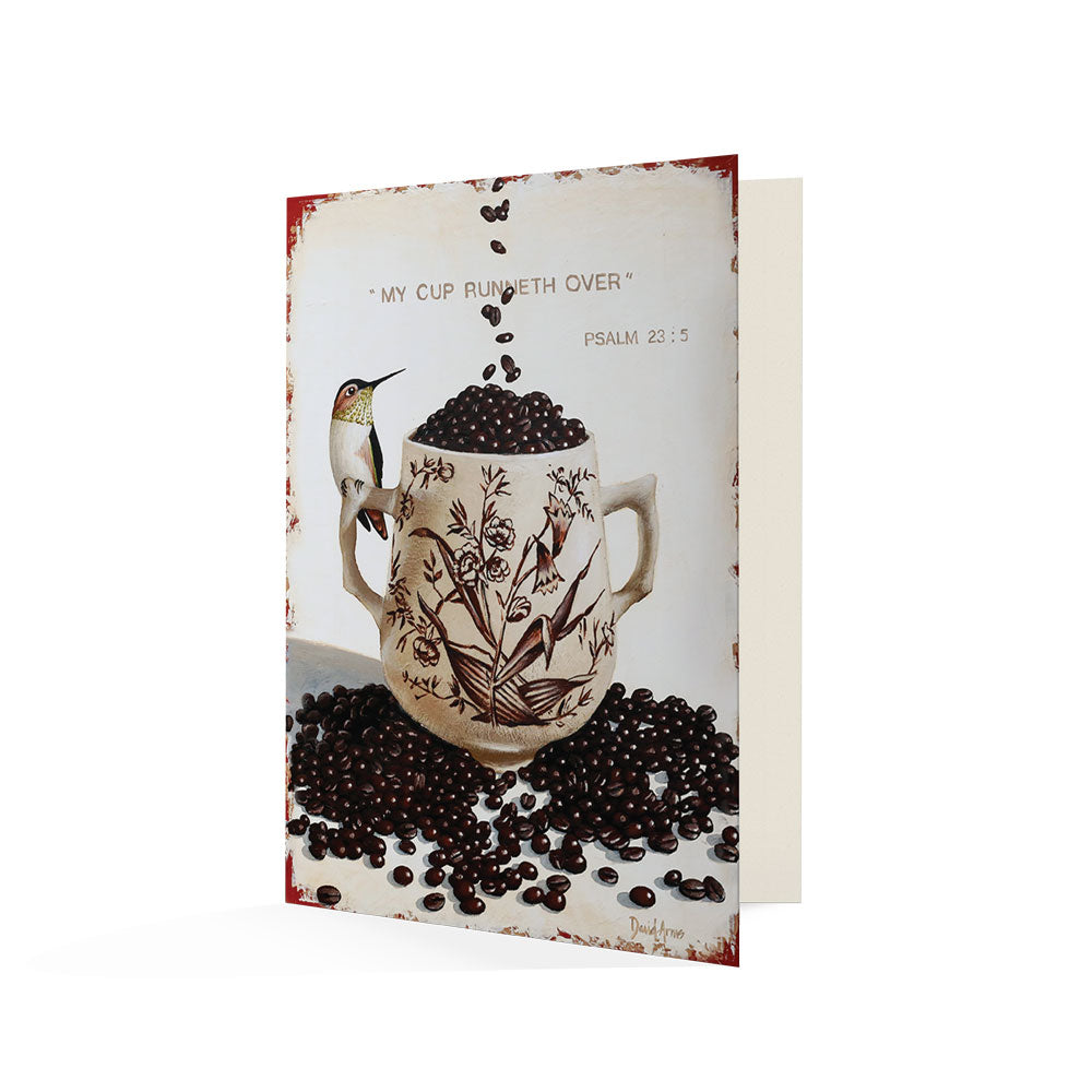 Sentence with product name and brand name: An illustration of the My Cup Runneth Over (Coffee Beans) Notecard surrounded by coffee beans with a hummingbird and the phrase "my cup runneth over - psalm 23:5" written on a handwritten note for that personal, by David Arms.