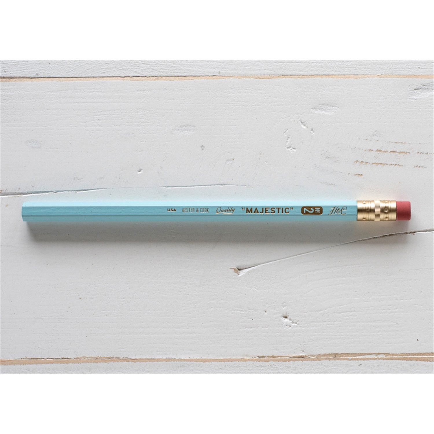A Hester & Cook jumbo hex pencil with a gold tip on a wooden surface.