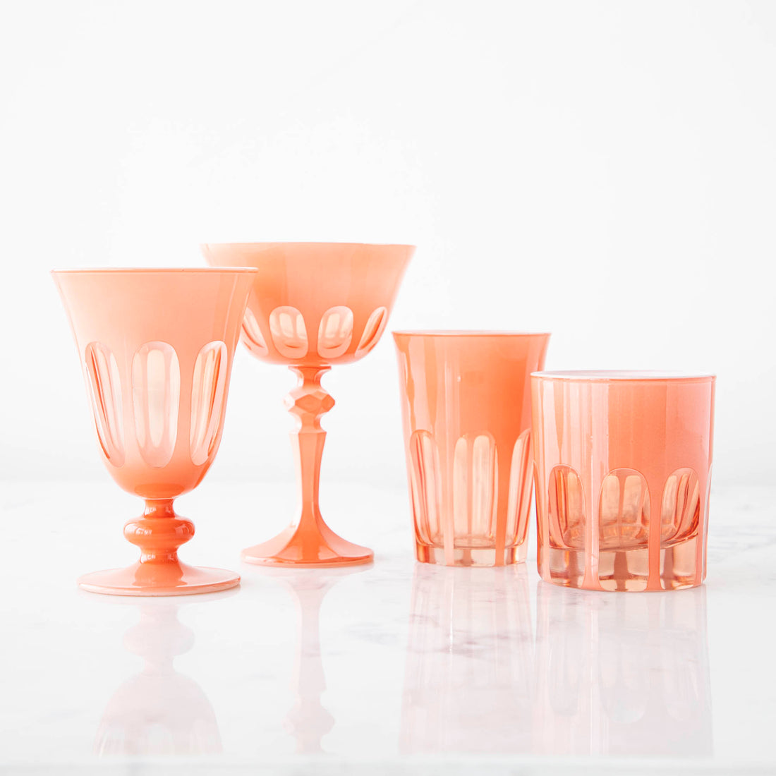 A set of four Rialto Salmon Glasses by SIR/MADAM on a white surface.