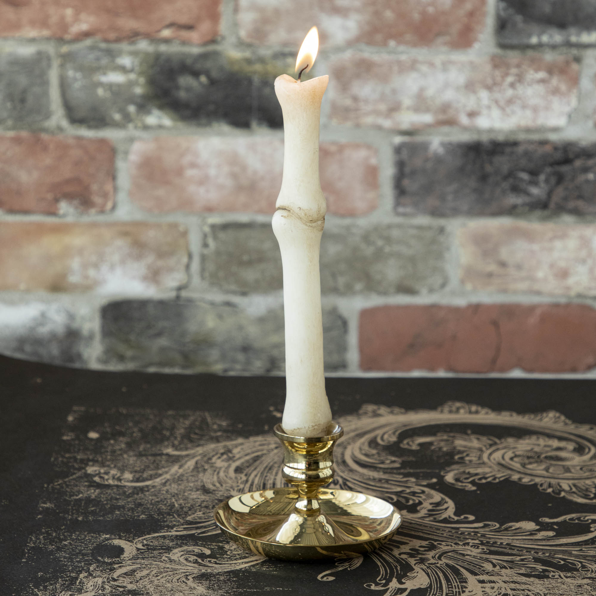 Stacked bone shaped taper candle in a brass candle holder.