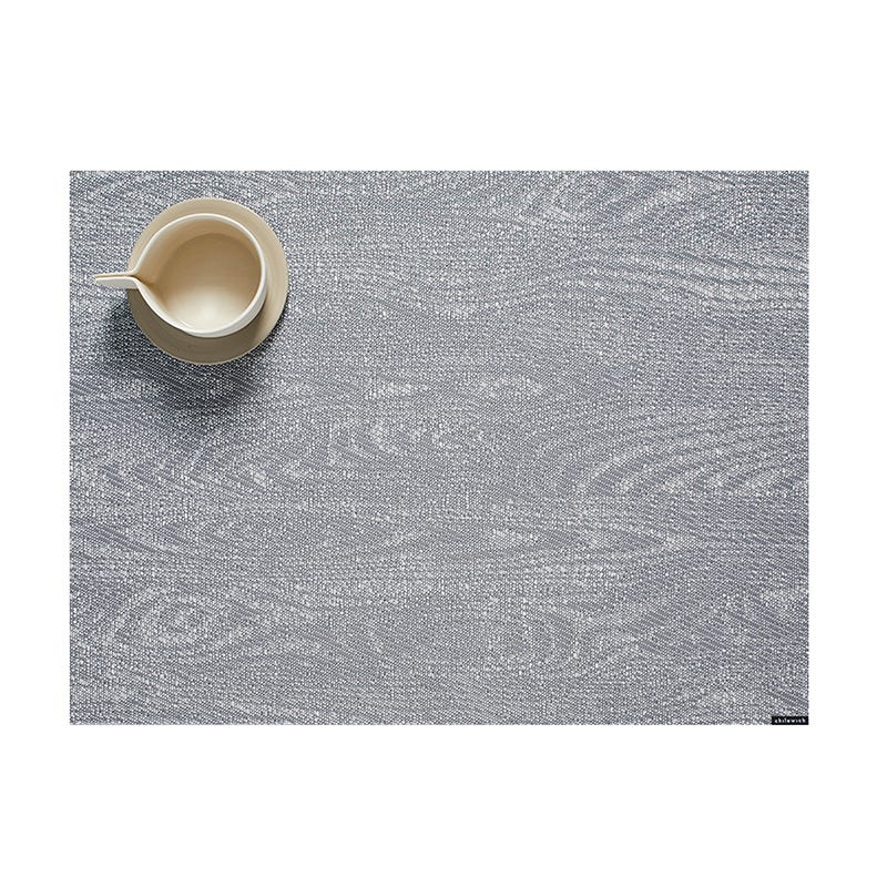 A ceramic jug placed on a textured Chilewich Woodgrain Table Mat with ample negative space, suitable for indoor-outdoor use.