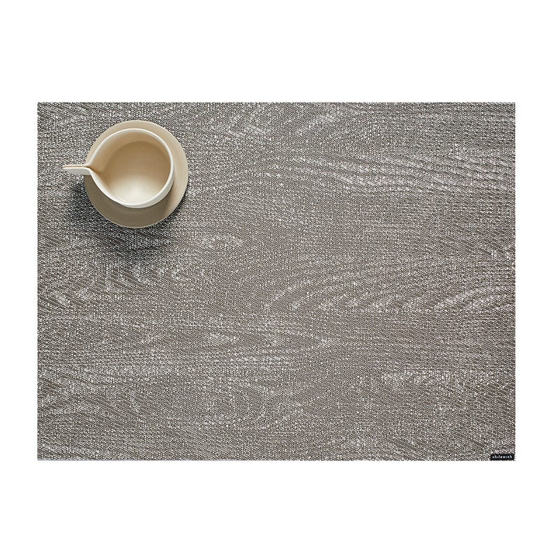 A ceramic jug placed on a textured Chilewich Woodgrain Table Mat with ample negative space, suitable for indoor-outdoor use.