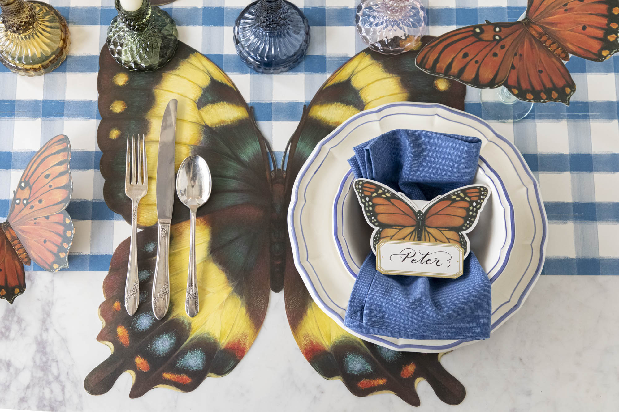 Elegant table setting with butterfly-themed decor and place cards on a black and white striped tablecloth.