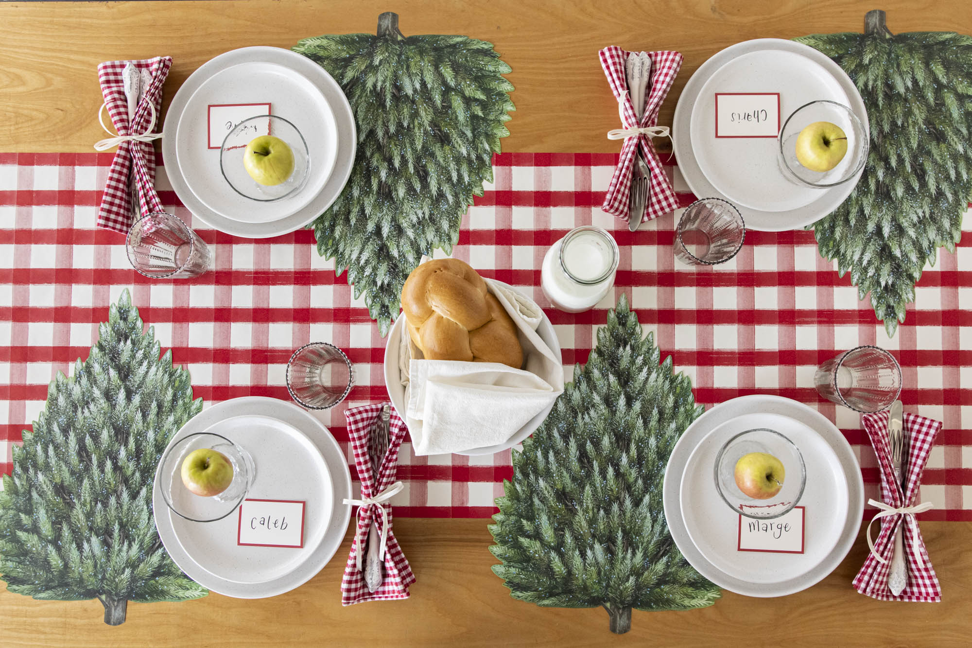 A winter themed table setting featuring the Die-cut Evergreen Placemat on the Red Painted Check Runner.