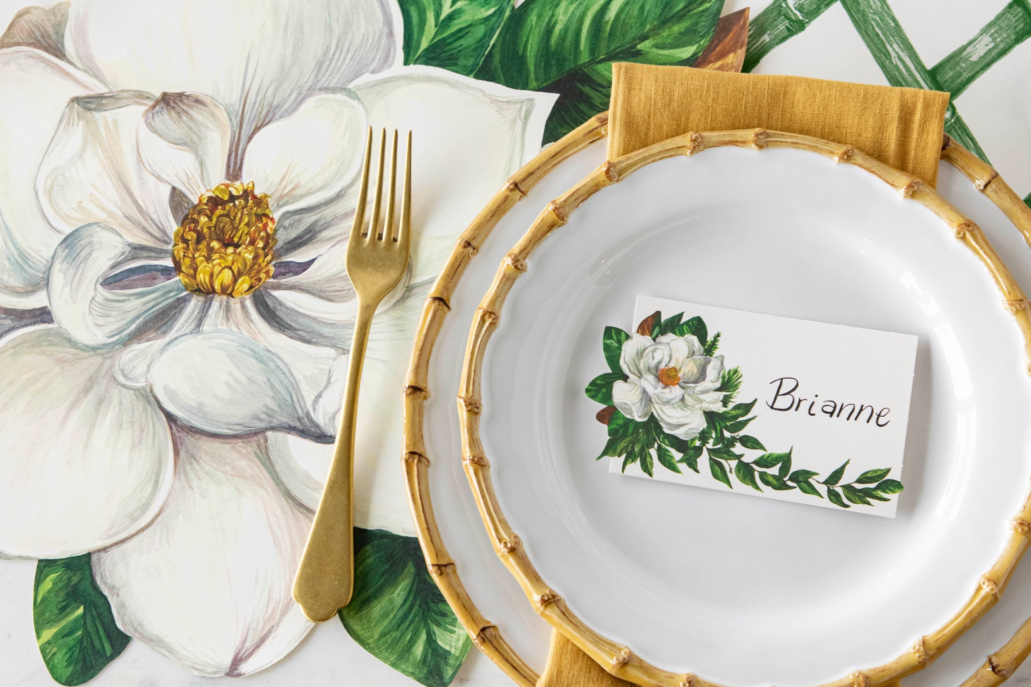 Elegant table setting with floral-patterned plates and matching tablecloth.