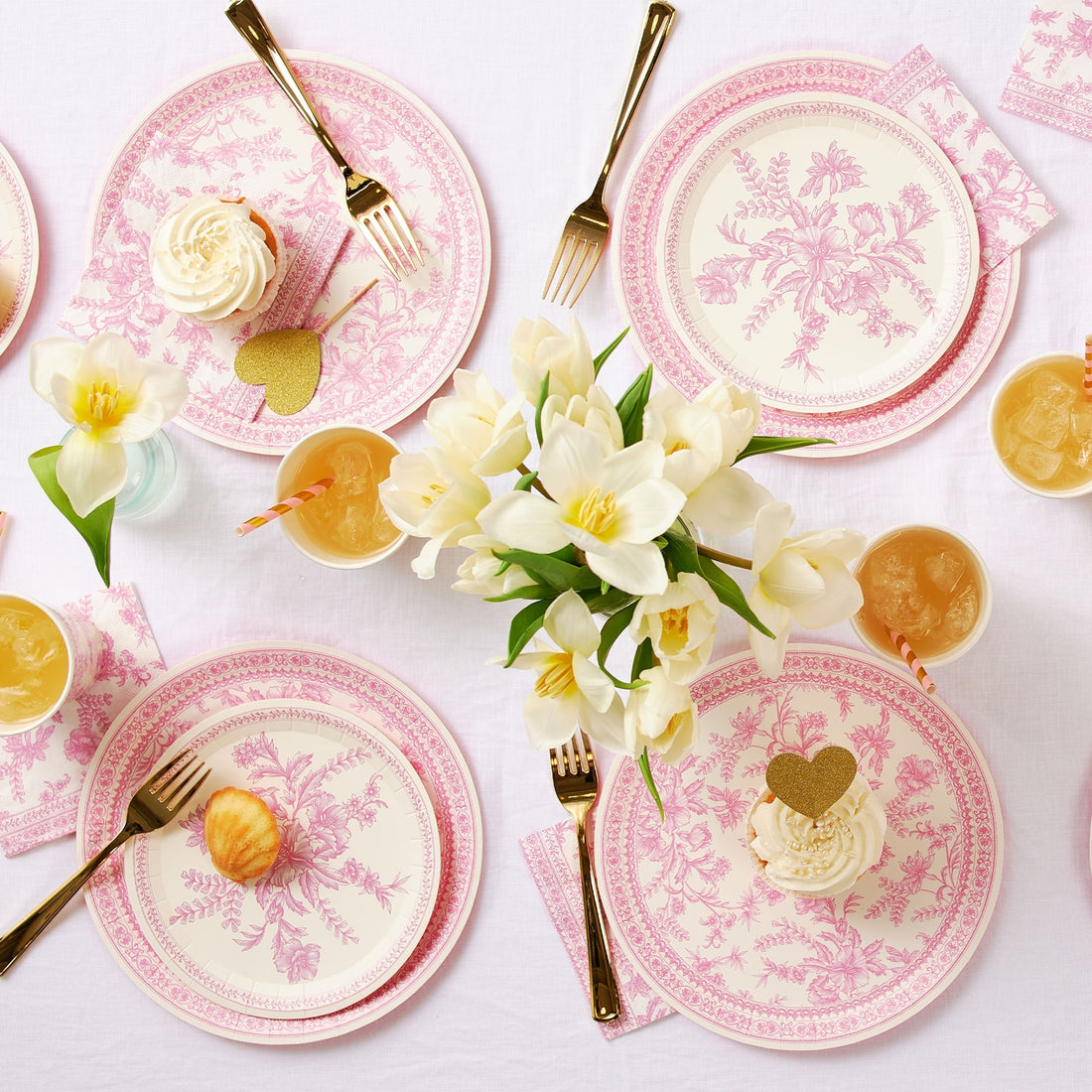 A table set with Pink French Toile Paper Party Dinnerware plates from Coterie Party Supplies featuring floral toile dinnerware patterns that evoke the charm of the French countryside, complemented by silverware.