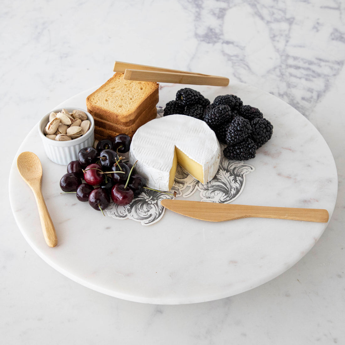 A plate with cheese, fruit, and nuts on it, served with BIA Mini Bamboo Utensils.