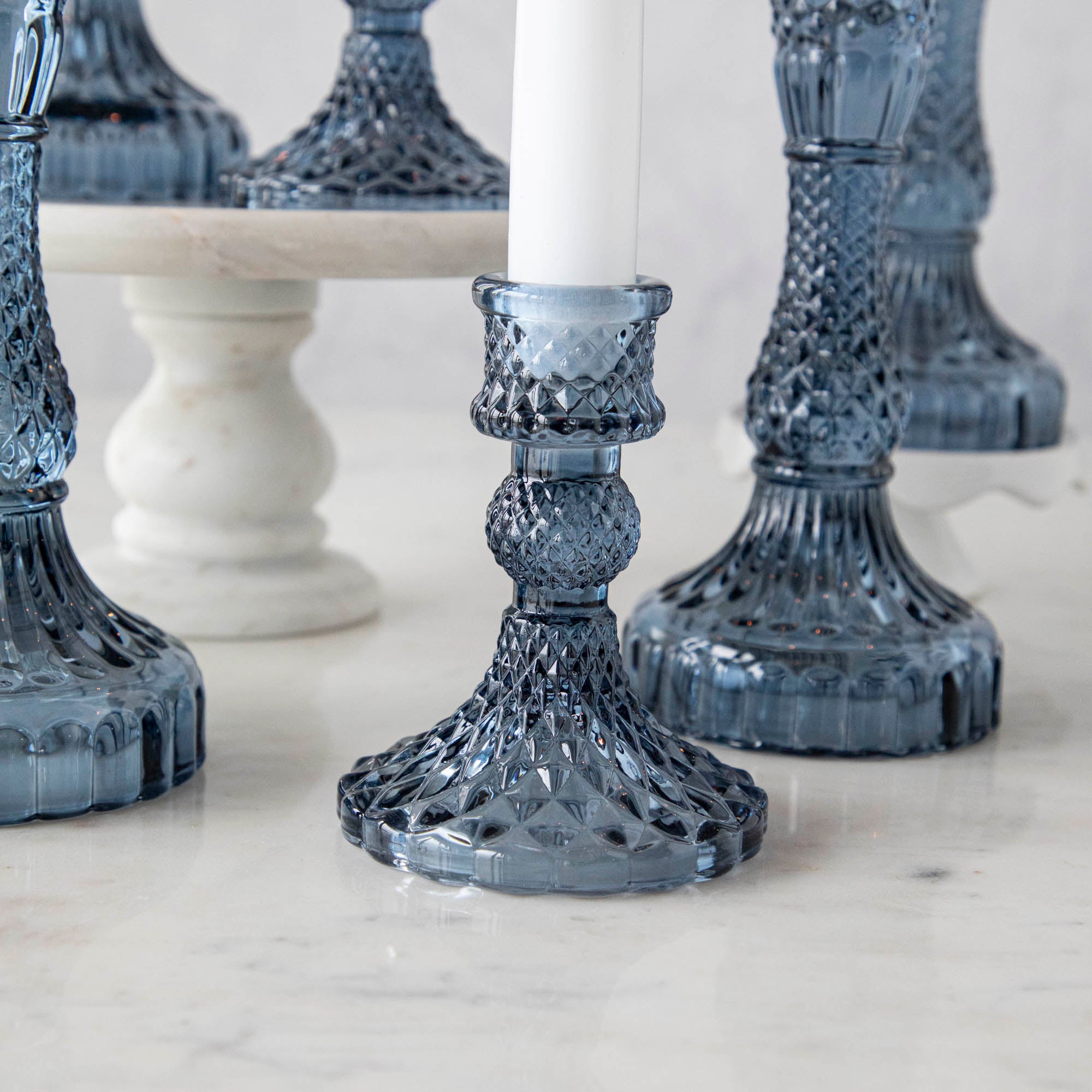 A group of Accent Decor Vintage Blue Candlestick candle holders on a marble table.