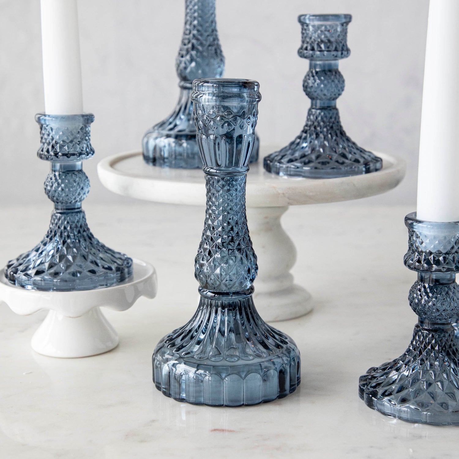 A group of Accent Decor Vintage Blue Candlestick candle holders on a marble table.