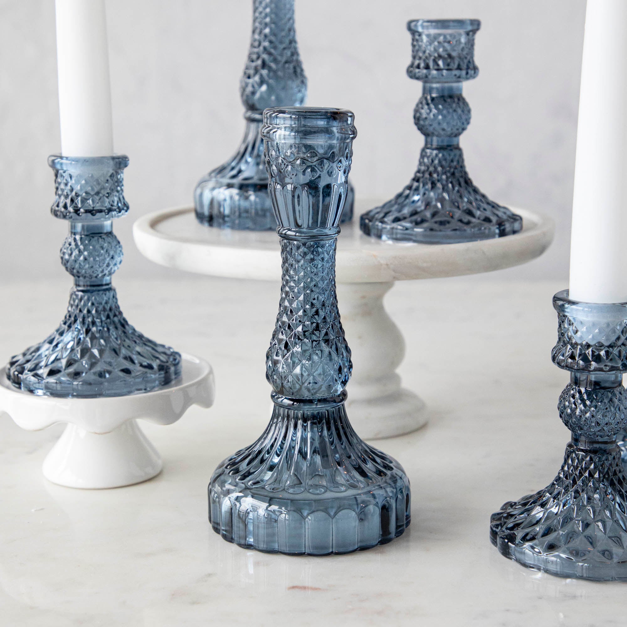 A group of Accent Decor Vintage Blue Candlestick candle holders on a marble table.