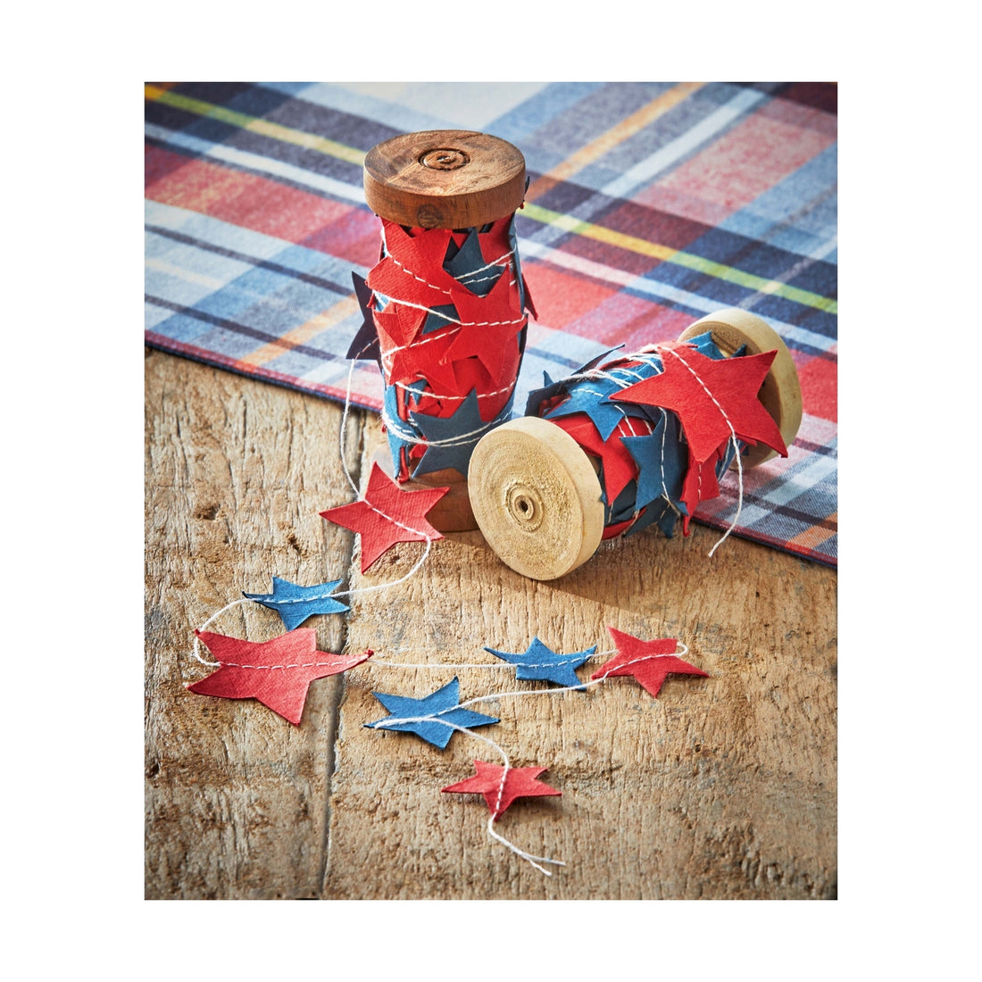 Red and blue stars made of paper sewn onto a string wrapped around a wood spool.