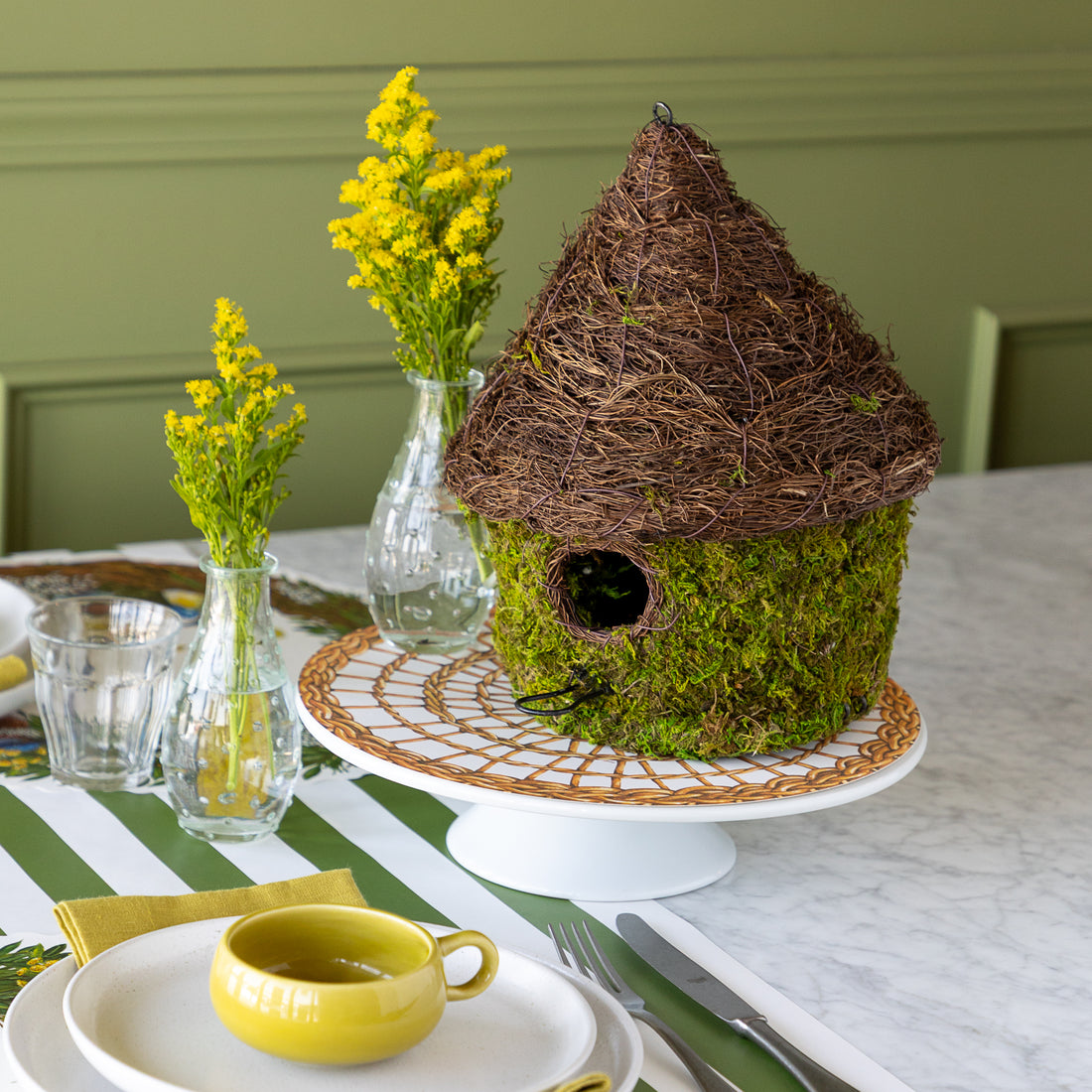 Bungalow Bird House made with moss on a table setting. 