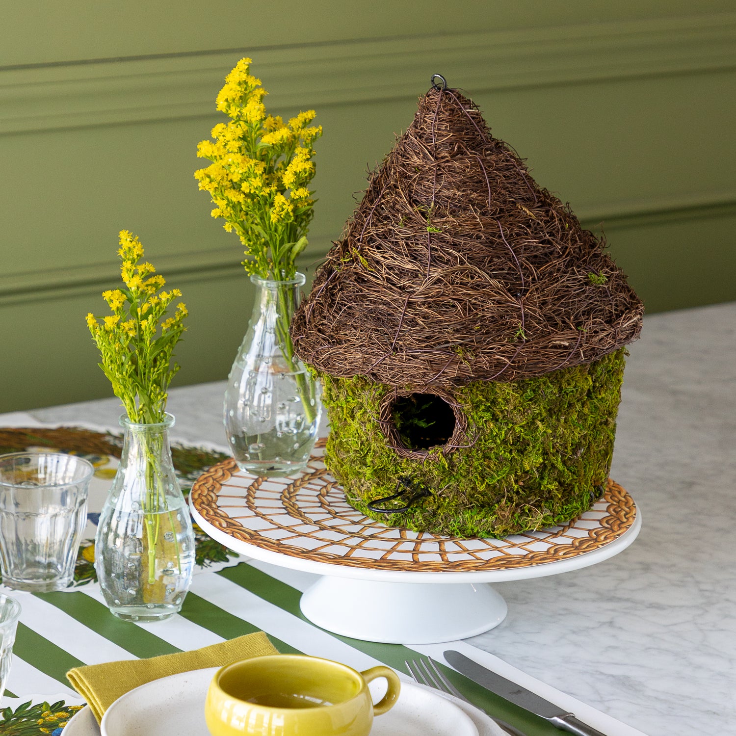 Bungalow Bird House made with moss on a table setting. 