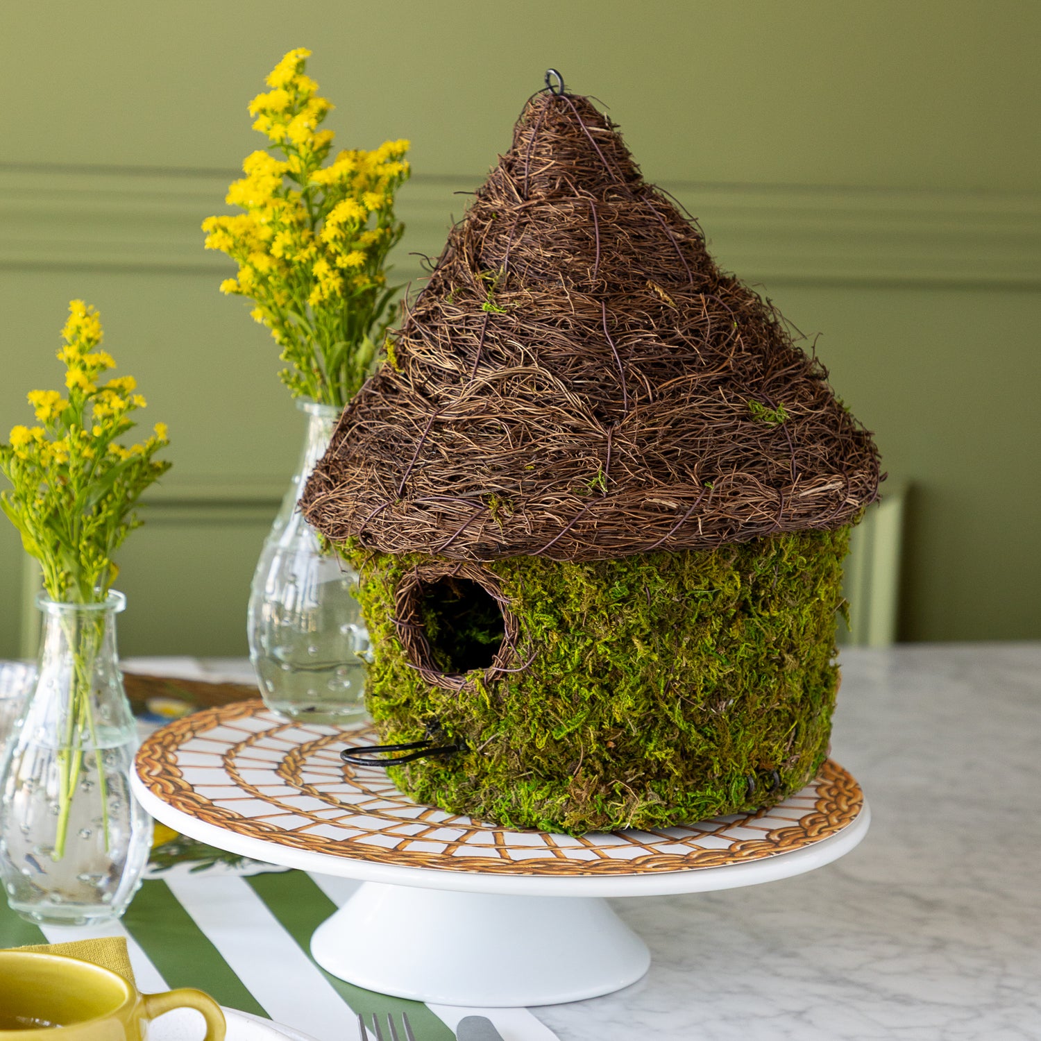 Bungalow Bird House made with moss on a table setting. 