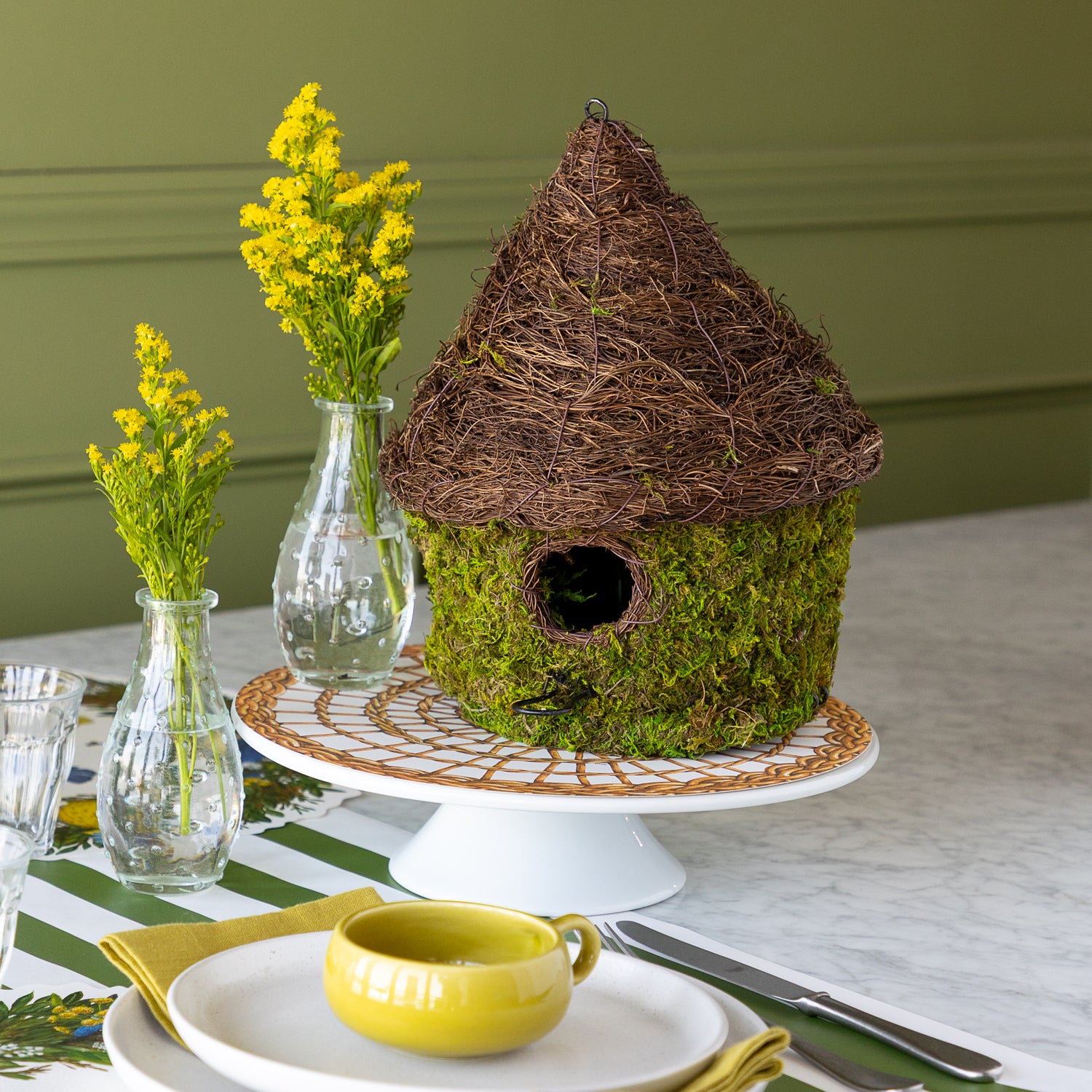 Bungalow Bird House made with moss on a table setting. 