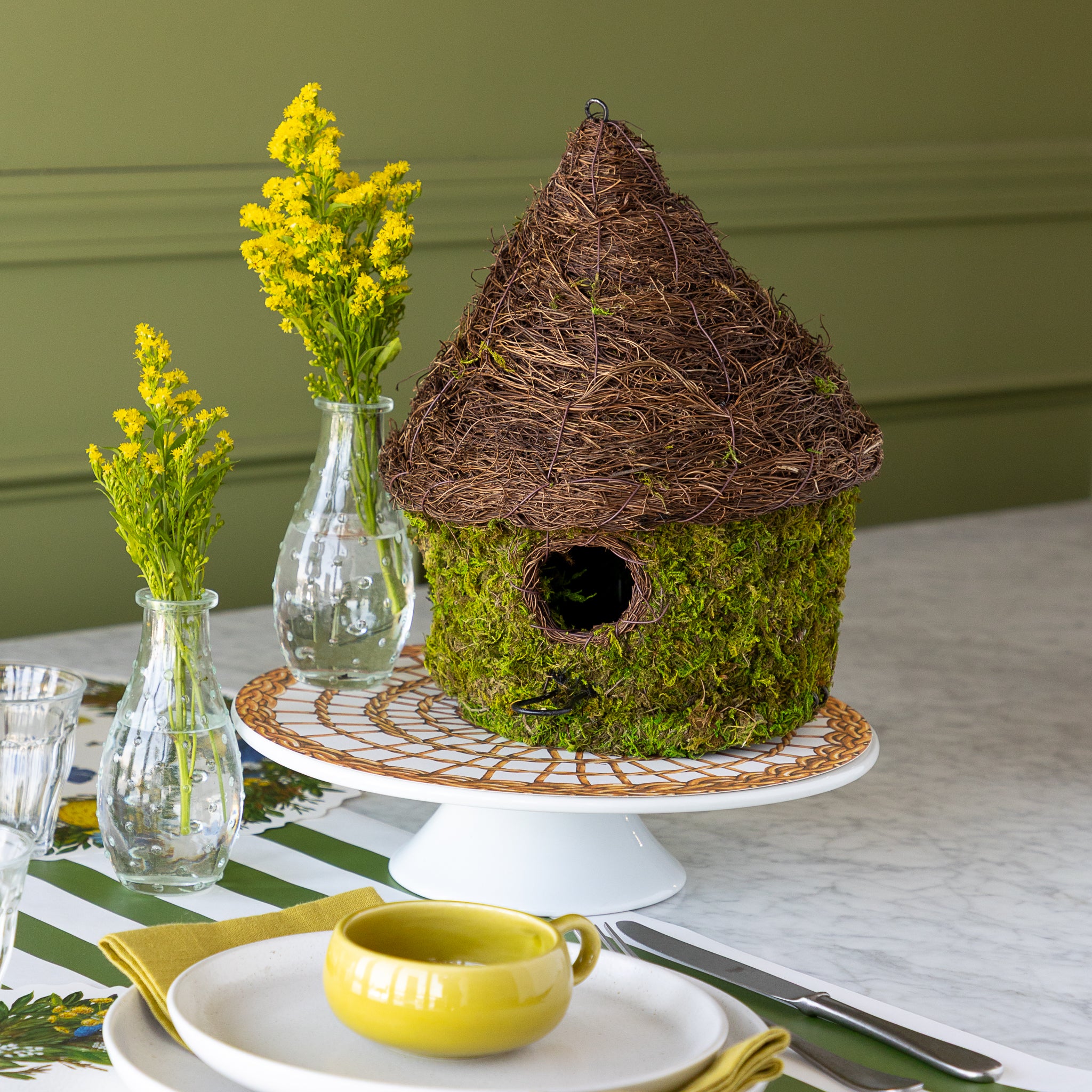 Bungalow Bird House made with moss on a table setting. 