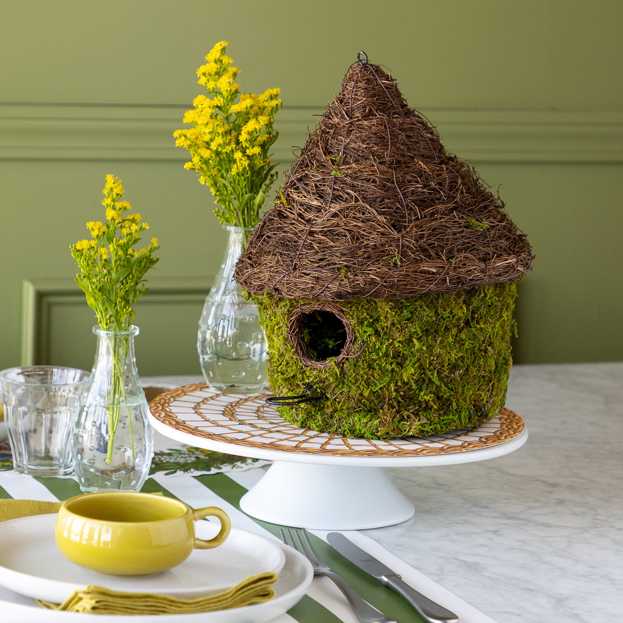 Bungalow Bird House made with moss on a table setting. 