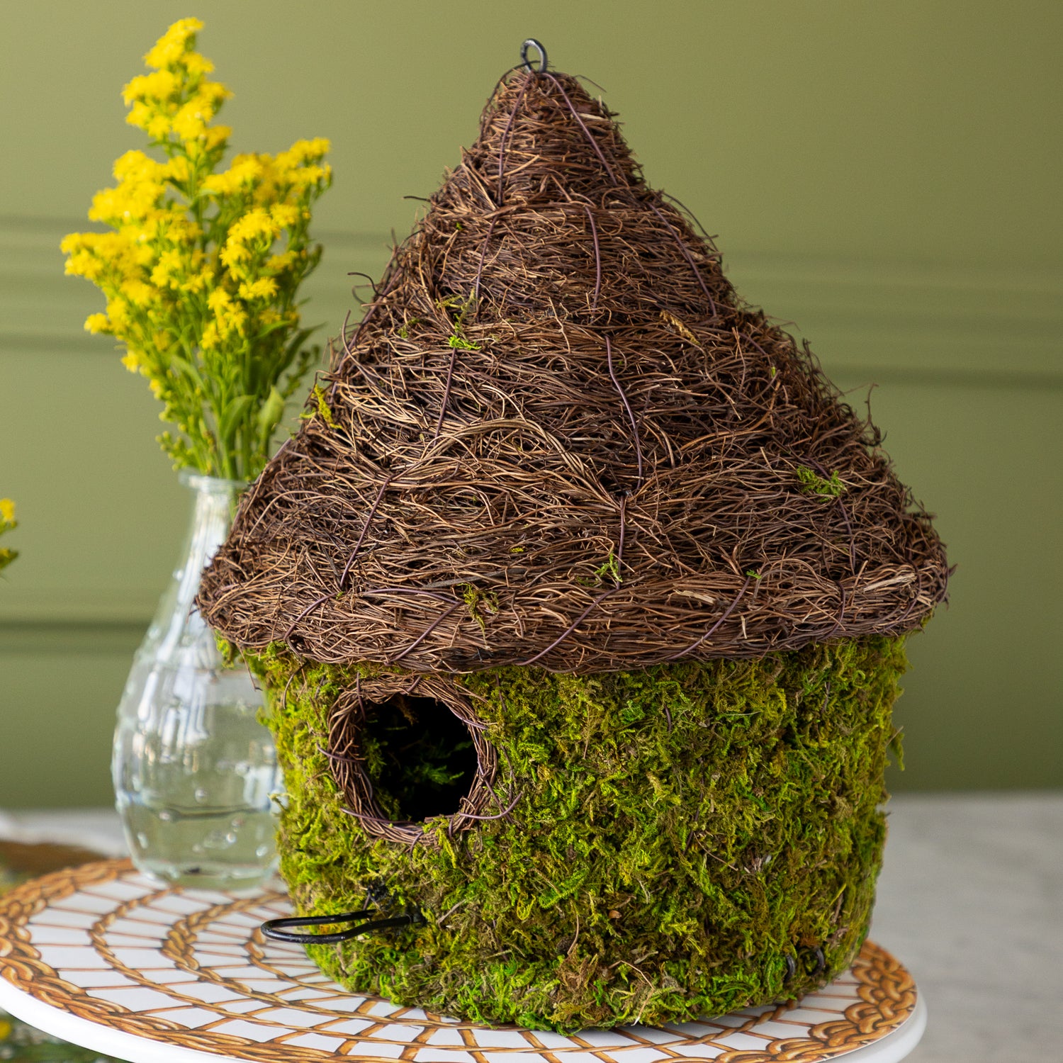Bungalow Bird House made with moss on a table setting. 