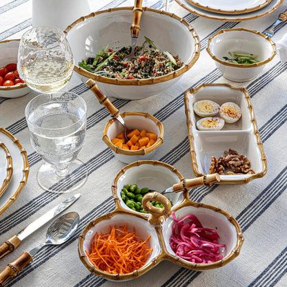 Elegant table setting featuring a variety of salads and appetizers with gold-trimmed, hand-painted Juliska ceramic  Classic Natural Bamboo Serving Pieces.