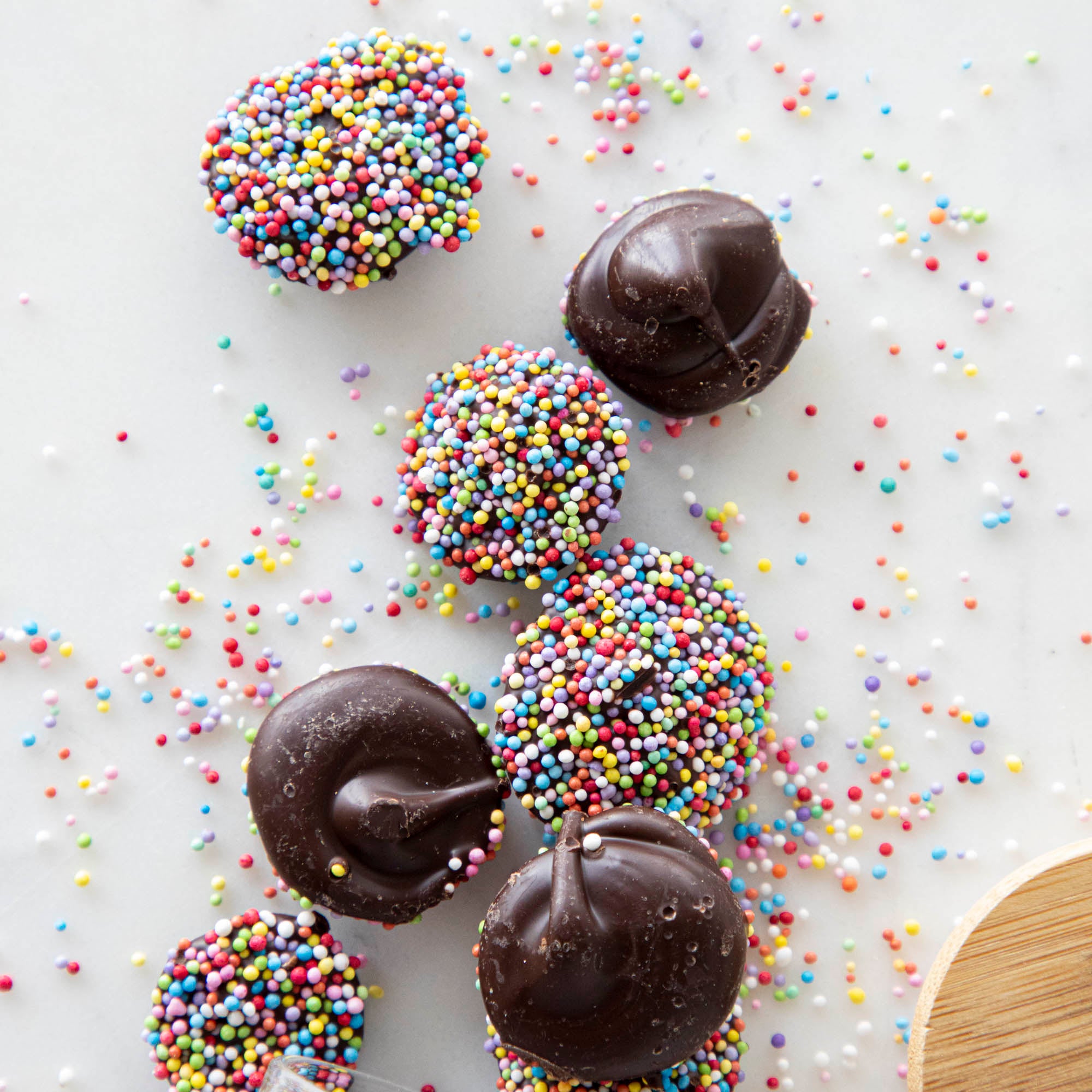 Hester &amp; Cook Chocolate Buttons covered natural nonpareils on a white surface.
