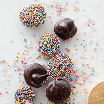 Hester &amp; Cook Chocolate Buttons covered natural nonpareils on a white surface.