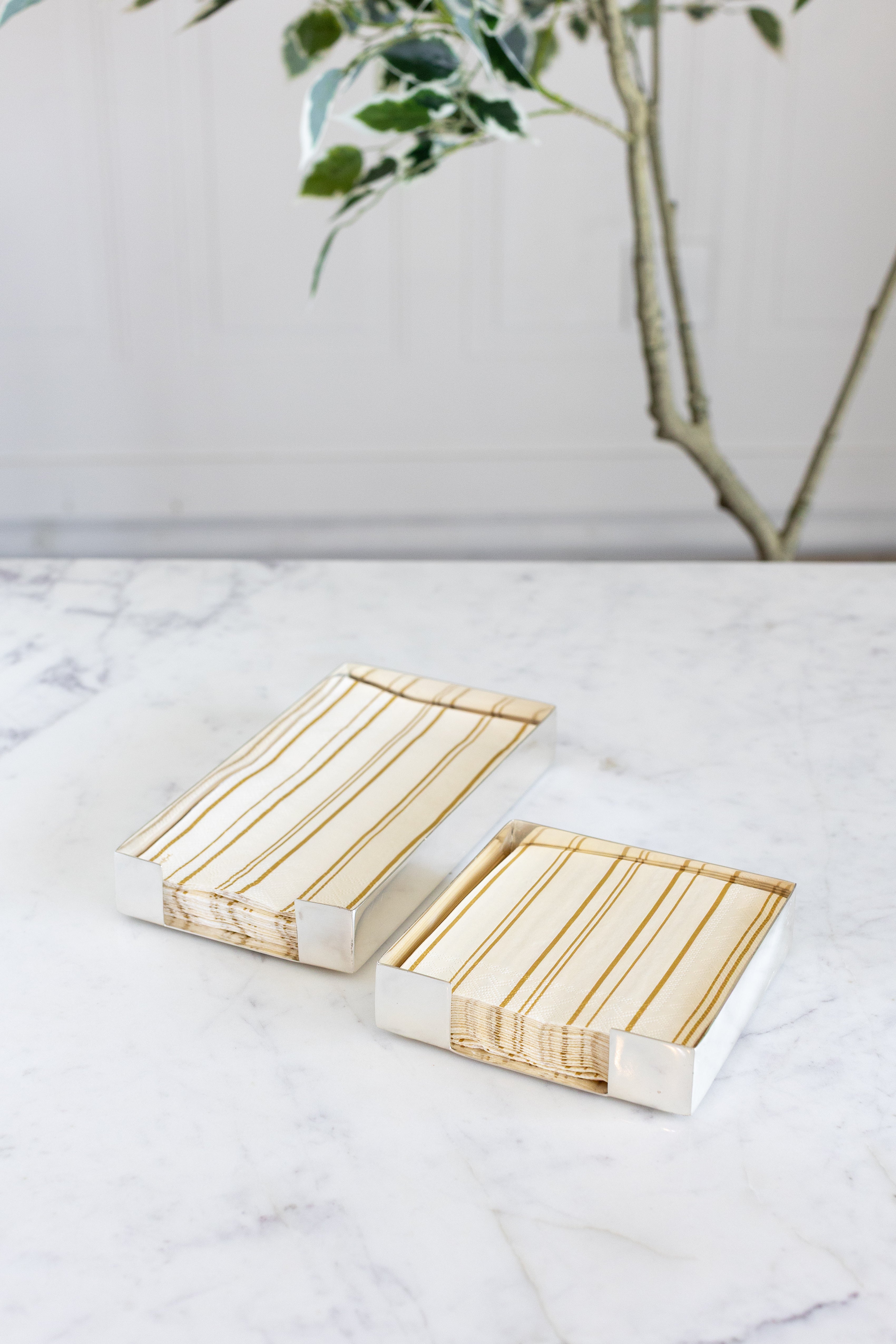 Two Silver Napkin Holders, guest-sized and cocktail-sized, containing napkins on a white table.
