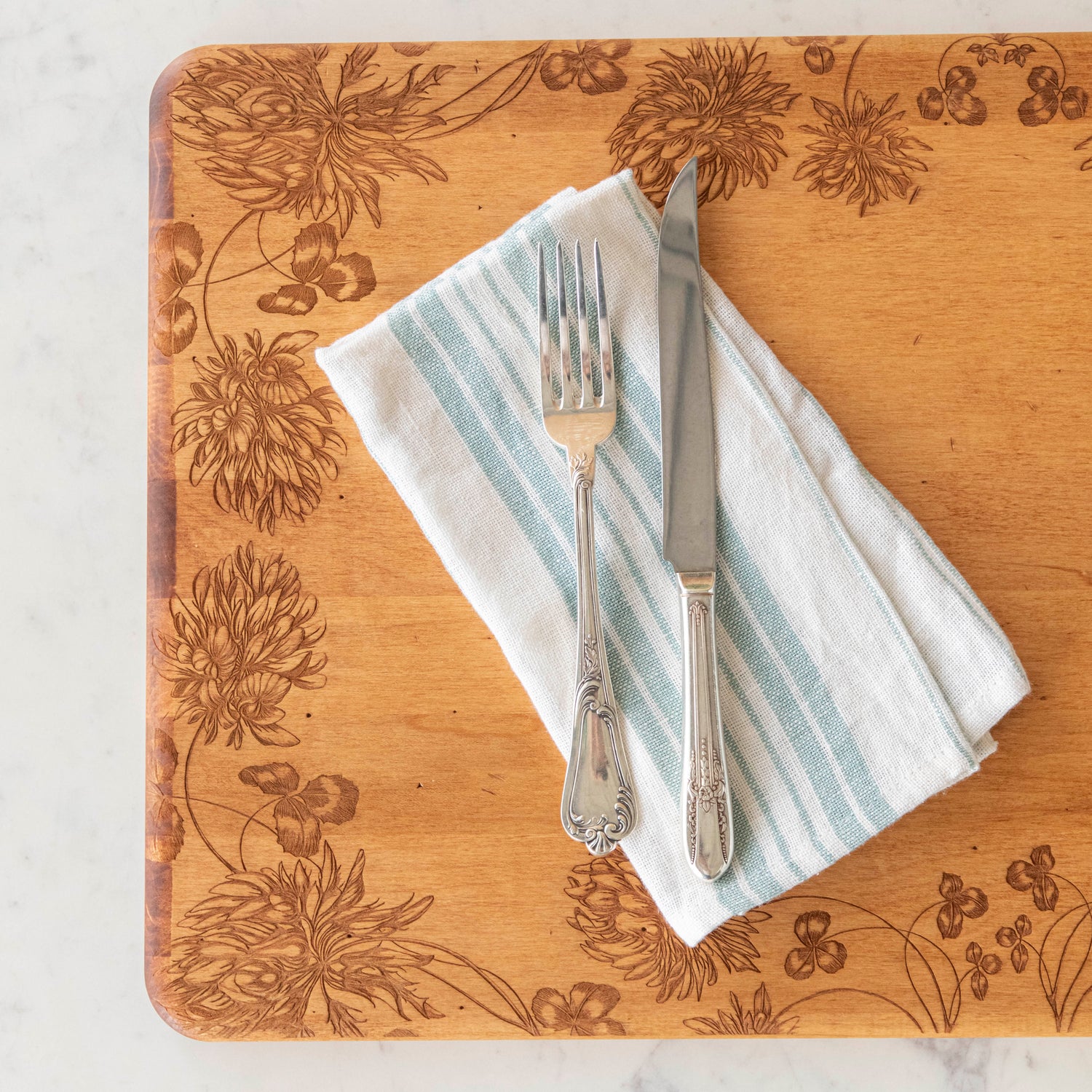 24 x 14 x 0.6 in maple artisan charcuterie board with heirloom distressed finish and hand-engraved clovers on a white background.