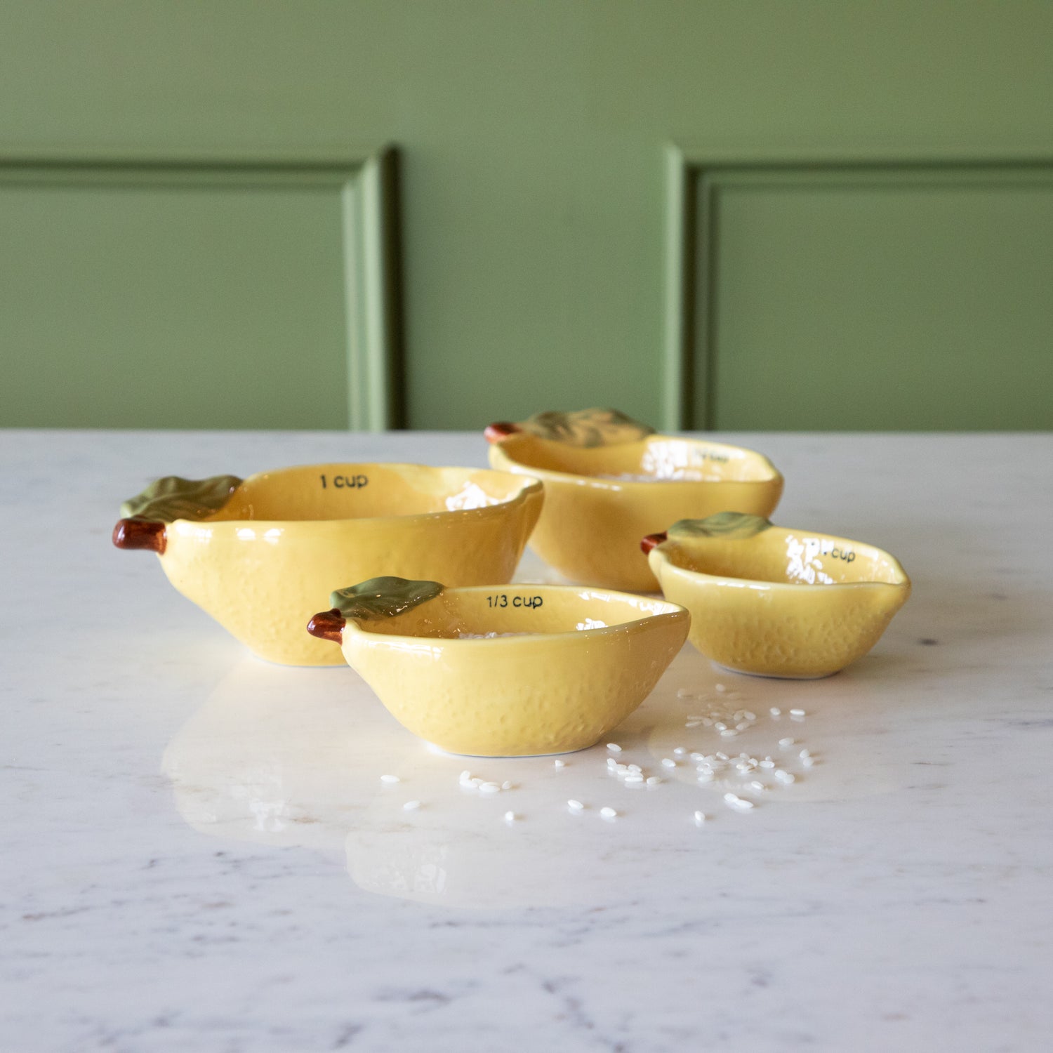 Stoneware Lemon Measuring Cups, Set of 4 with rice in two of the cups and some grains scattered on the table.