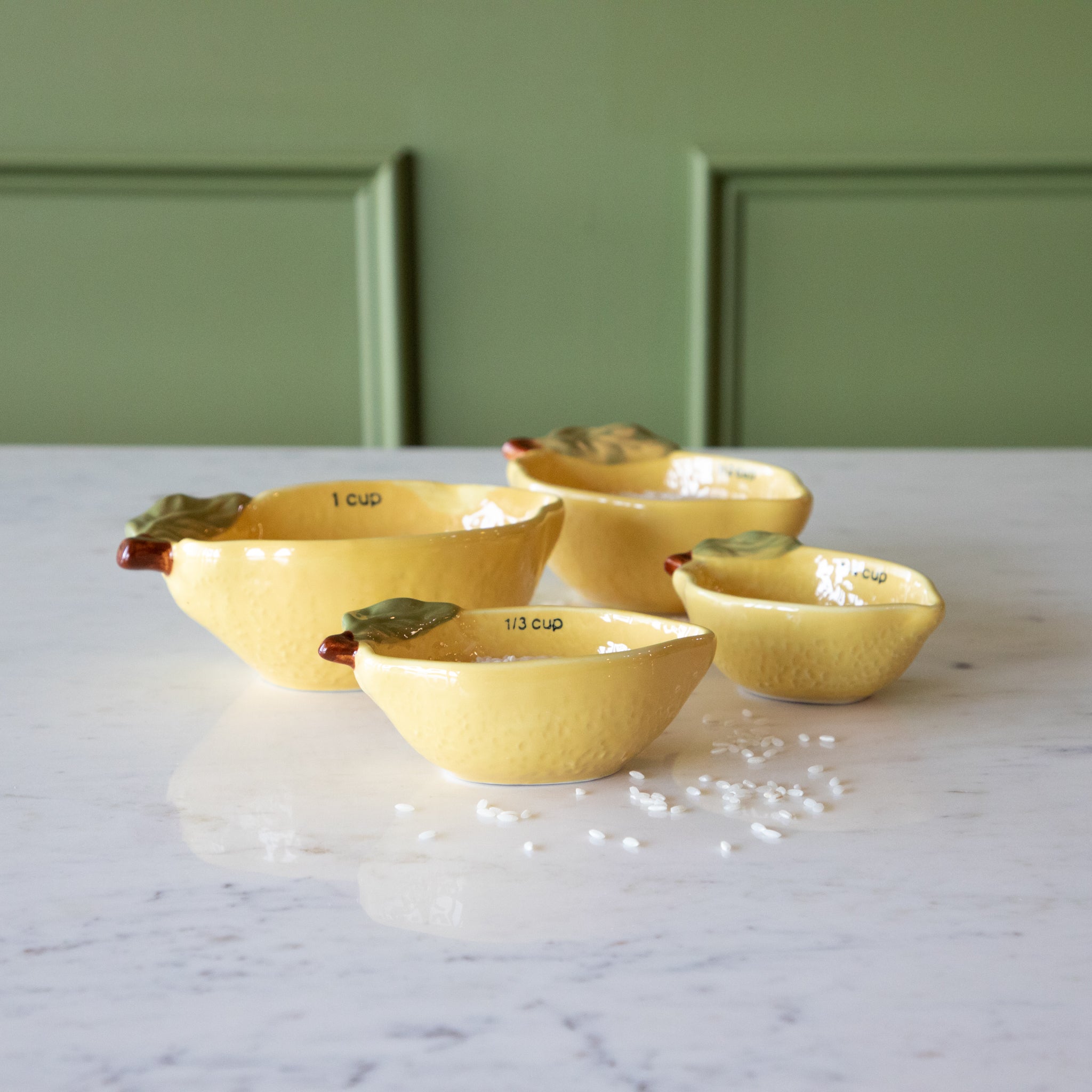 Stoneware Lemon Measuring Cups, Set of 4 with rice in two of the cups and some grains scattered on the table.