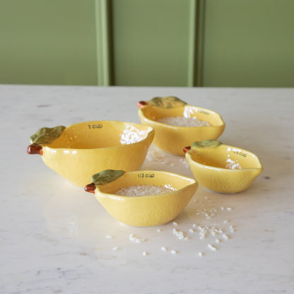 Stoneware Lemon Measuring Cups, Set of 4 with rice in two of the cups and some grains scattered on the table.