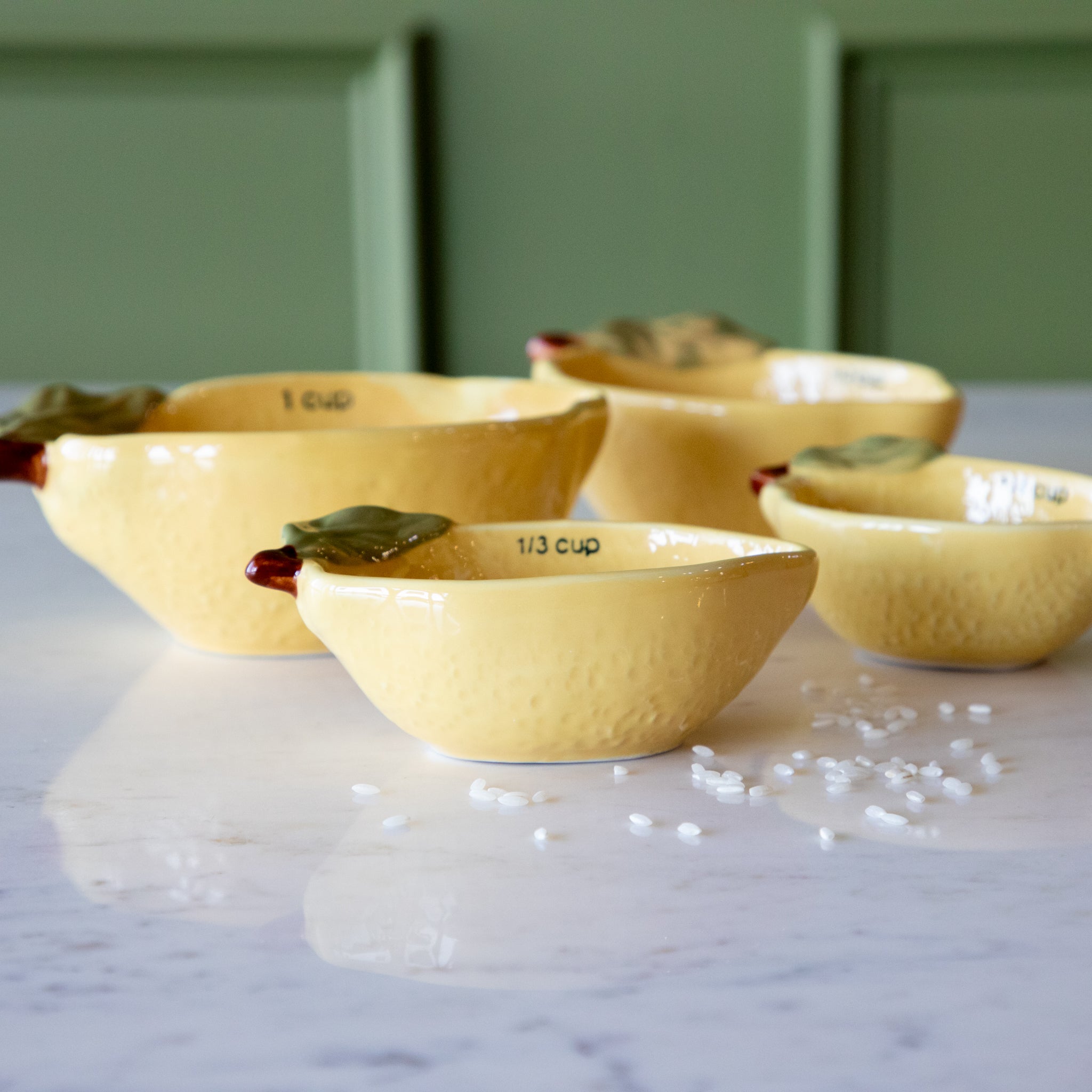 Stoneware Lemon Measuring Cups, Set of 4 with rice in two of the cups and some grains scattered on the table.