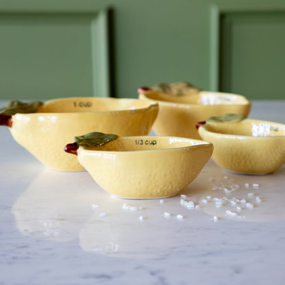 Stoneware Lemon Measuring Cups, Set of 4 with rice in two of the cups and some grains scattered on the table.