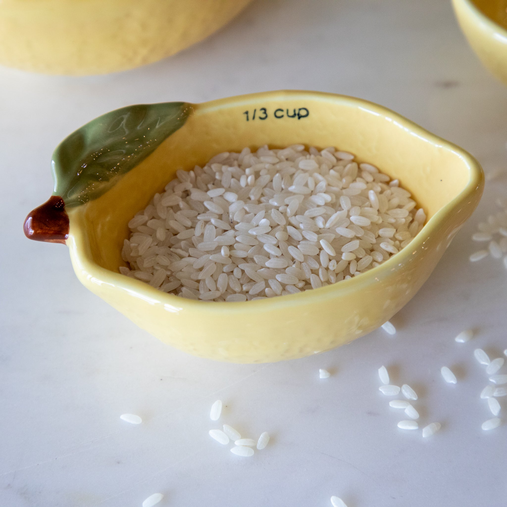 A close up of the 1/3 measuring cup showing the rice inside, 1/3 text, and the green leaf and brown stem.