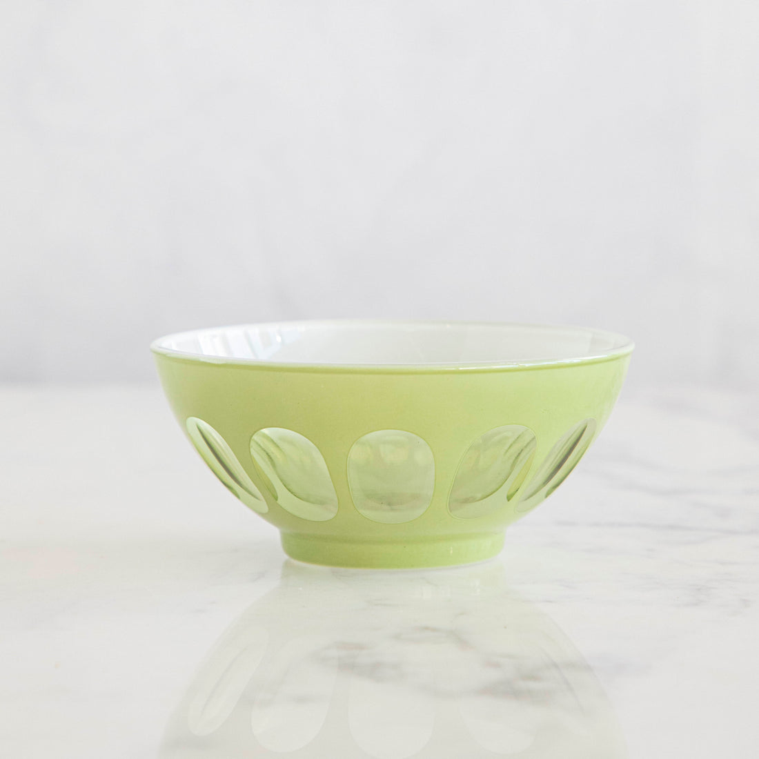 A Rialto Pale Sage Glass Bowl on a marble table.