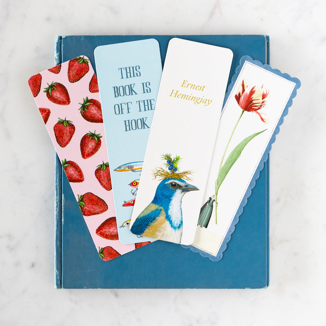 A blue book with four Hester & Cook bookmarks atop.