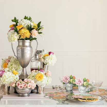 The Die-cut Garden Trophy Placemat in an elegant table setting for four, featuring a silver trophy in the floral centerpiece.