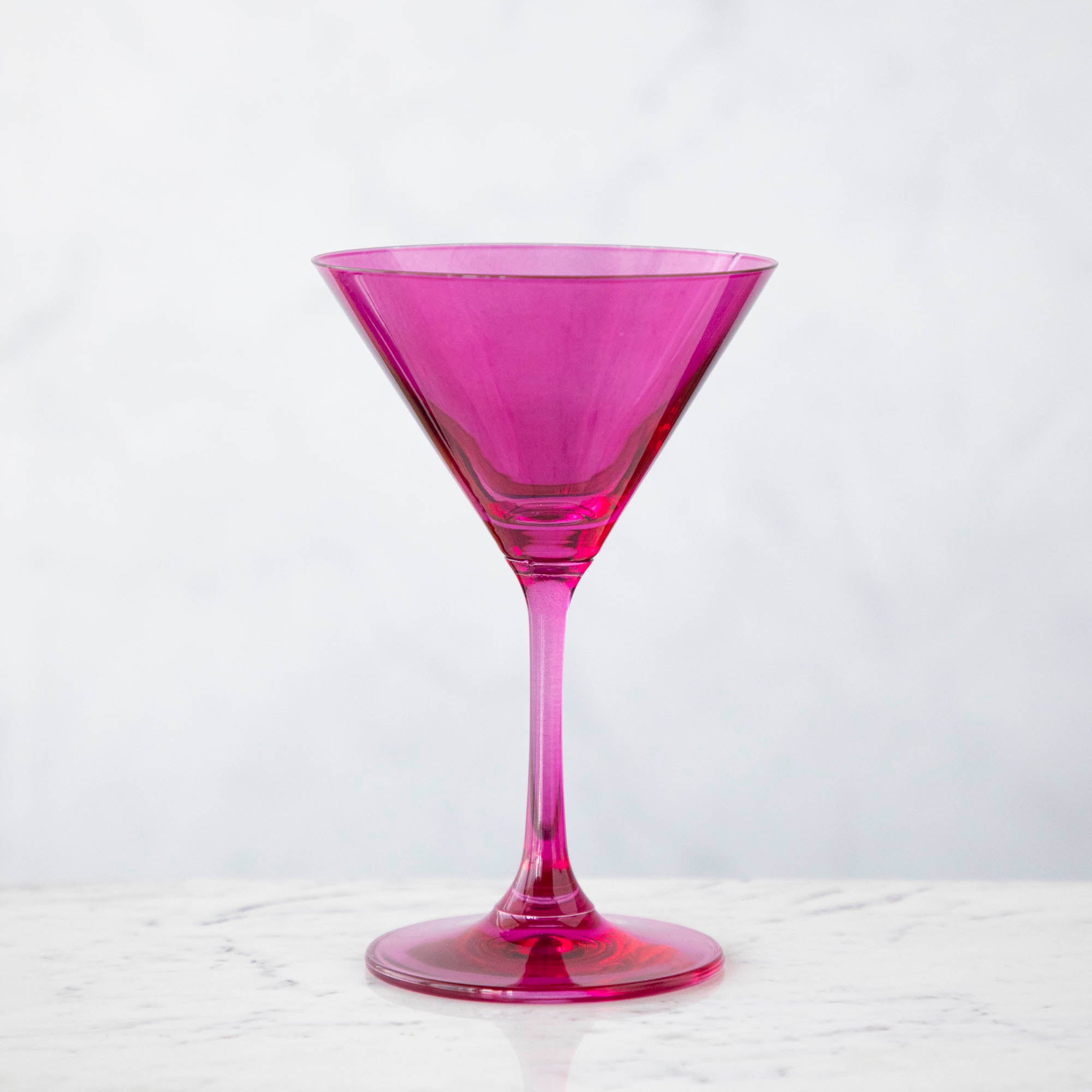 A pink crystal stemware wine glass on a marble table.