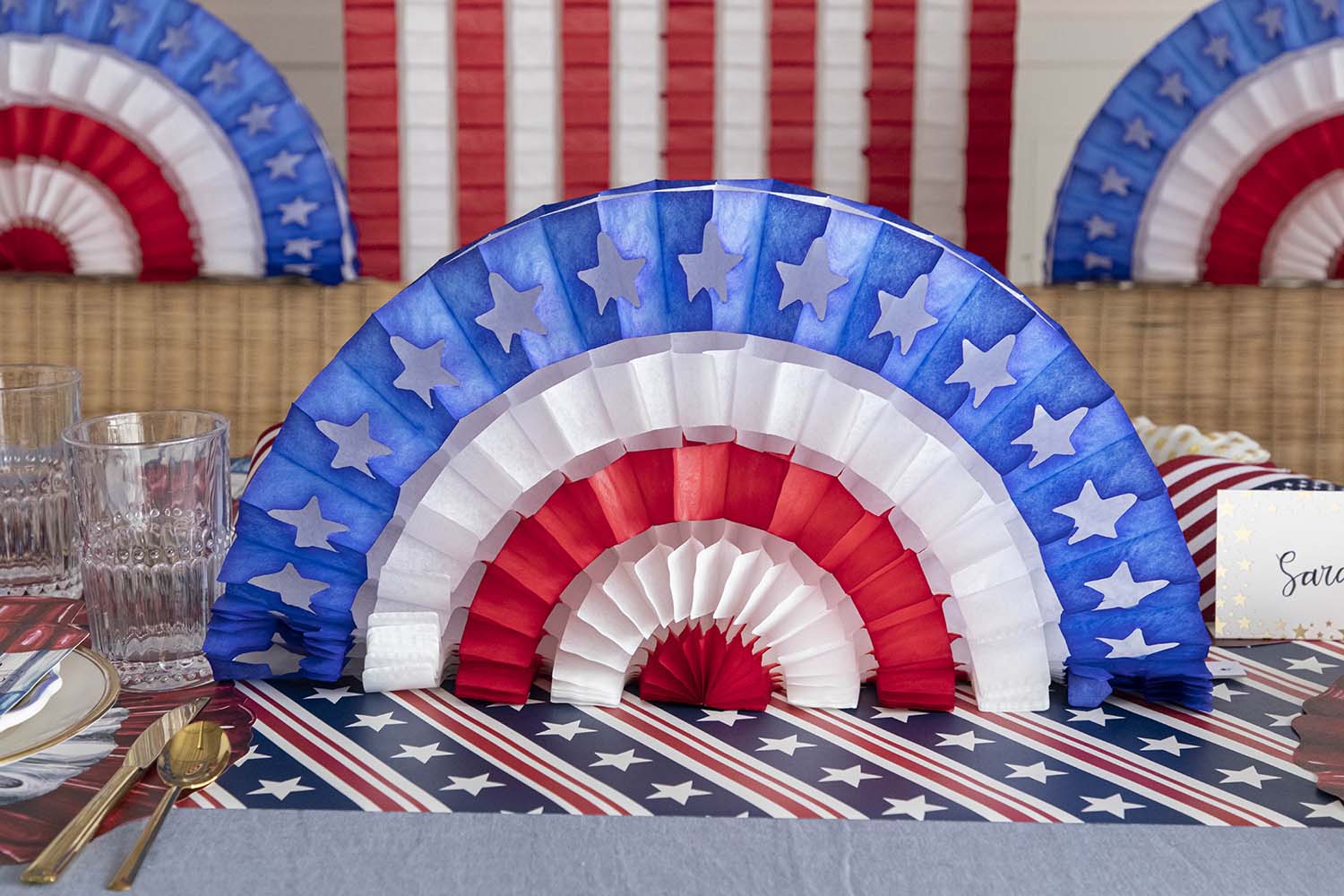 A patriotic party table set up with red, white, and blue Hester &amp; Cook Patriotic Star Fan decorations.