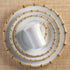 An overhead view of a stack of elegantly designed dishwasher safe Juliska Classic Natural Bamboo dinnerware with a bamboo motif, placed on a textured beige surface.