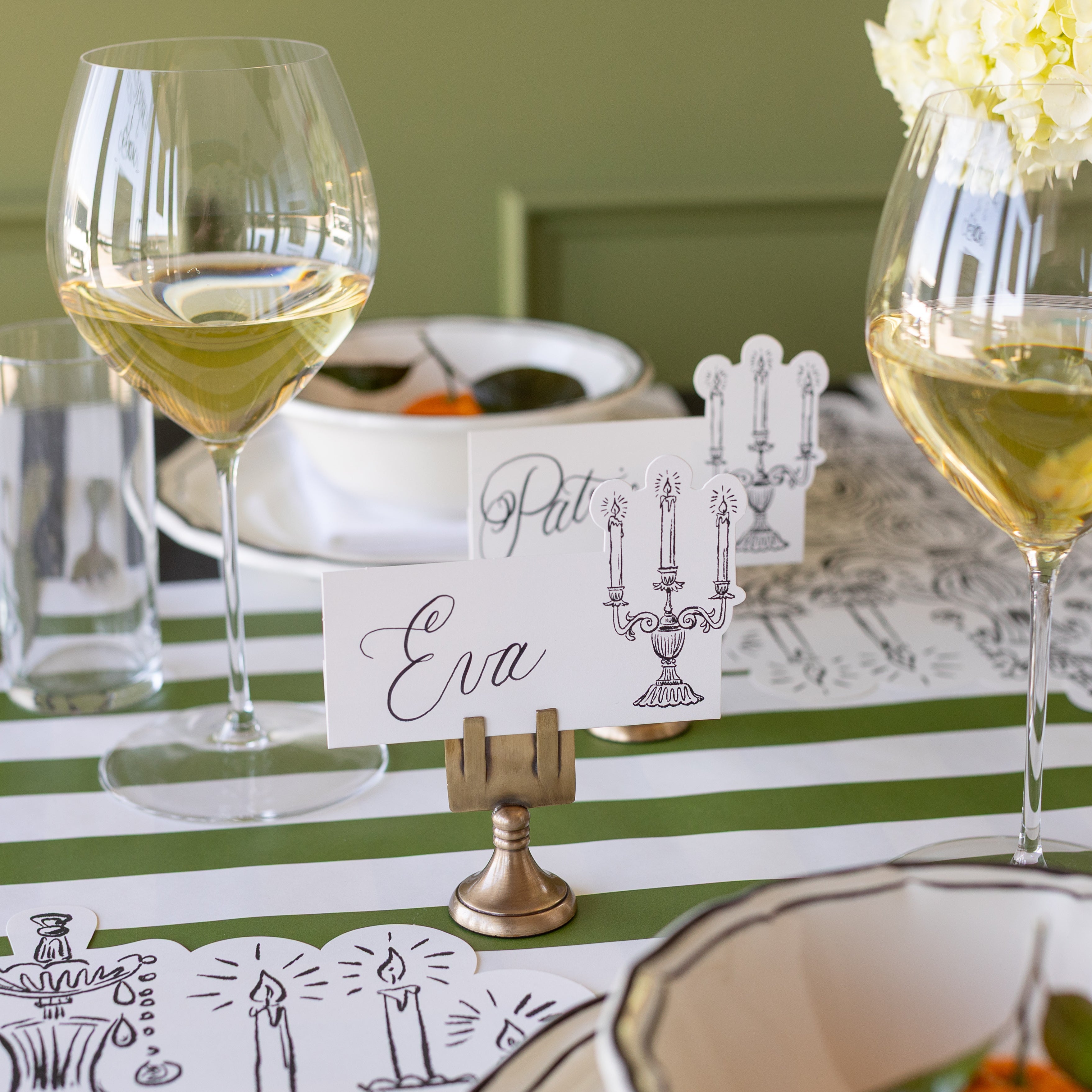 The Silver Place Card Holder holding the Candelabra Place Card with &quot;Eva&quot; written on it.