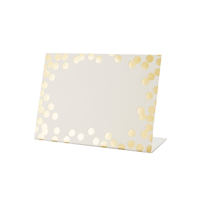 A white, rectangular freestanding place card featuring scattered gold foil dots adorning the edges.