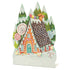 A die-cut, freestanding place card featuring whimsical artwork of a charming gingerbread house with snowy evergreen trees behind it and candy decor all around.