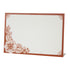 A free-standing, rectangular white table card with a dark orange frame around the edges, embellished with dark orange linework flower designs in the corners.