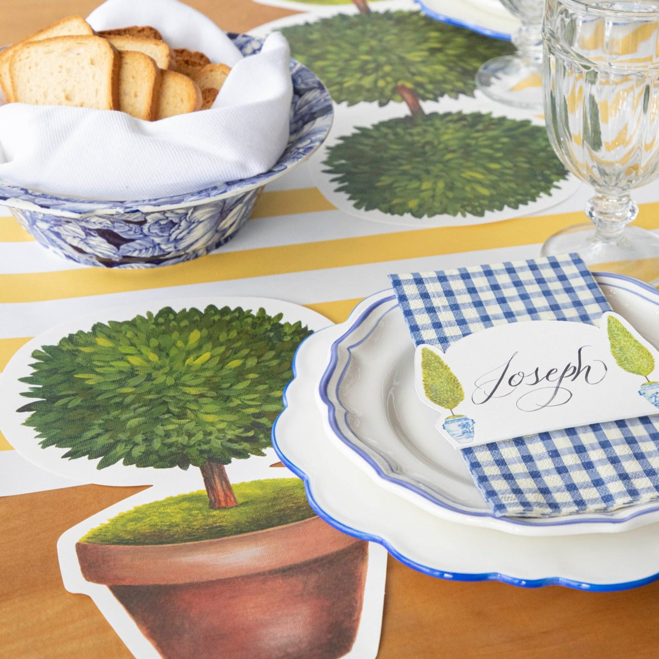 Two Die-cut Topiary Pair Placemats on a table with placemats on a white background. (Brand: Hester &amp; Cook)