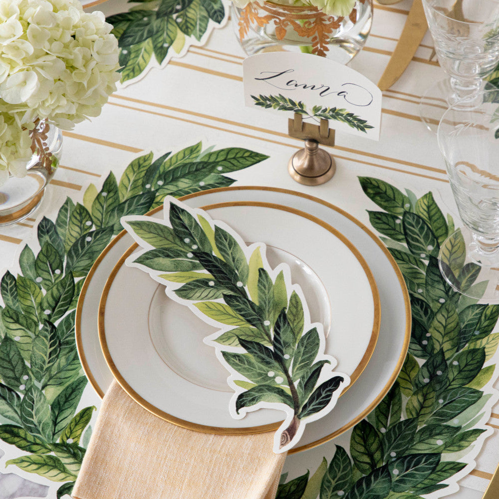 An elegant place setting with gold accents featuring a Laurel Table Accent resting on the plate.