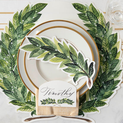 An elegant place setting with gold accents featuring a Laurel Table Accent resting on the plate.