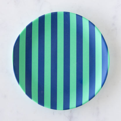 A round Stripe Melamine Plate with alternating vertical mint and navy stripes on a marble table.