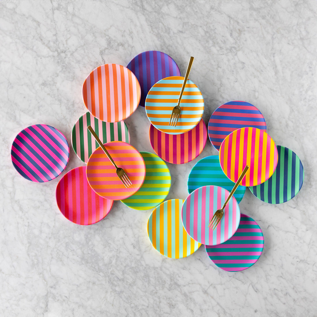 Colorful Stripe Melamine Plates are arranged on a marble surface, with three striped plates each holding a gold fork.