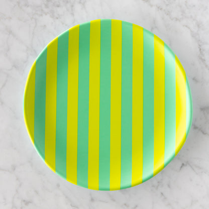 A round Stripe Melamine Plate with alternating vertical lime green and teal stripes on a marble table.